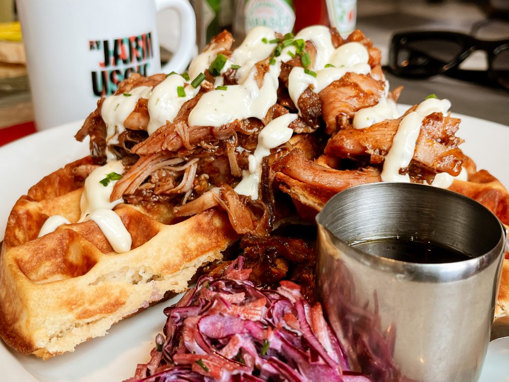 A plate of Chicken and Waffles with coleslaw and syrup